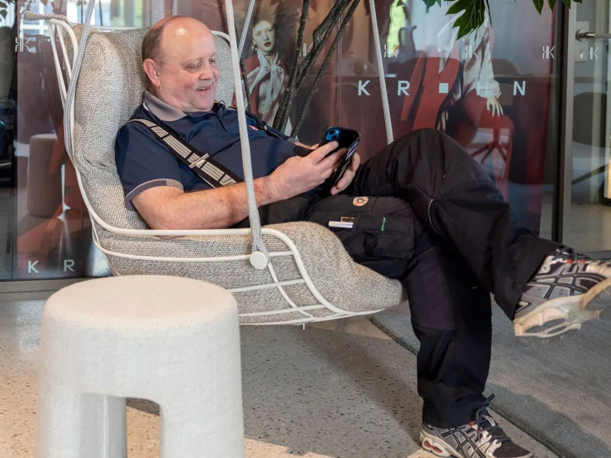 Guttorm Normann lener seg tilbake i en hengestol i et av Ragde Eiendoms bygg, smiler og ser på mobilen
