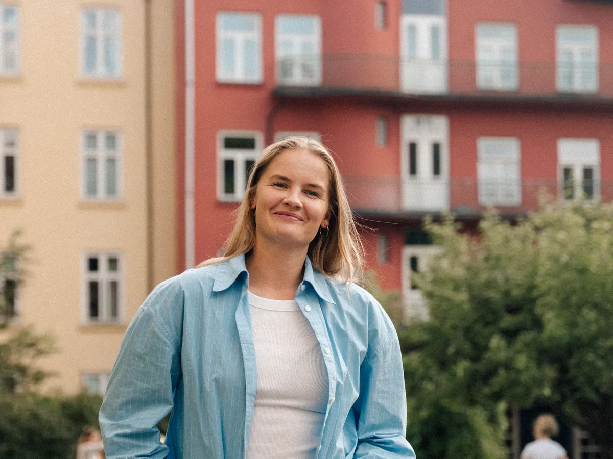 En beboer smiler foran bygårdene i borettslaget